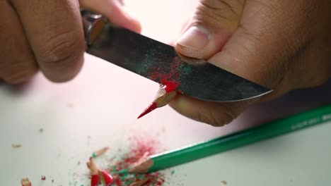 imágenes de manos afilando lentamente un lápiz y algunos lápices de colores con un cuchillo afilado