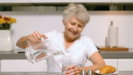 retired woman pouring a glass of water for breakfast