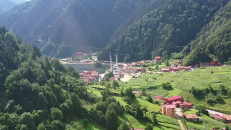 aerial drone flying over a large mountain forest hill revealing a beautiful lake and mosque in the village of uzungol trabzon turkey on a sunny summer day