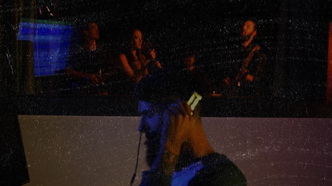 Male audio engineer seeing band on screen, adjusting faders, holding headphones, monitoring mix