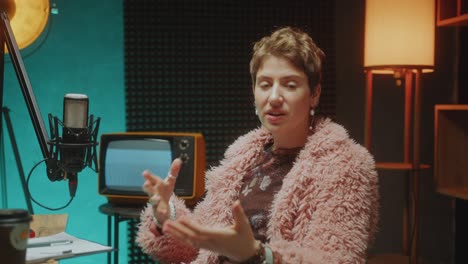 fashionable female podcaster talking on camera by mic in recording studio