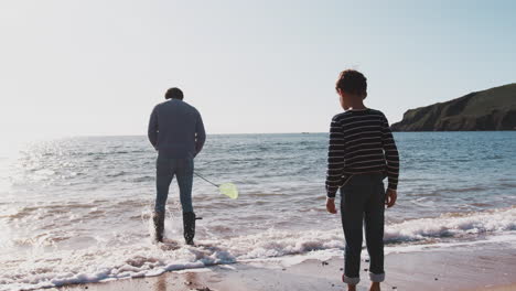 Vater-Und-Sohn-Spielen-Mit-Einem-Fischernetz,-Indem-Sie-Am-Strand-Wellen-Brechen