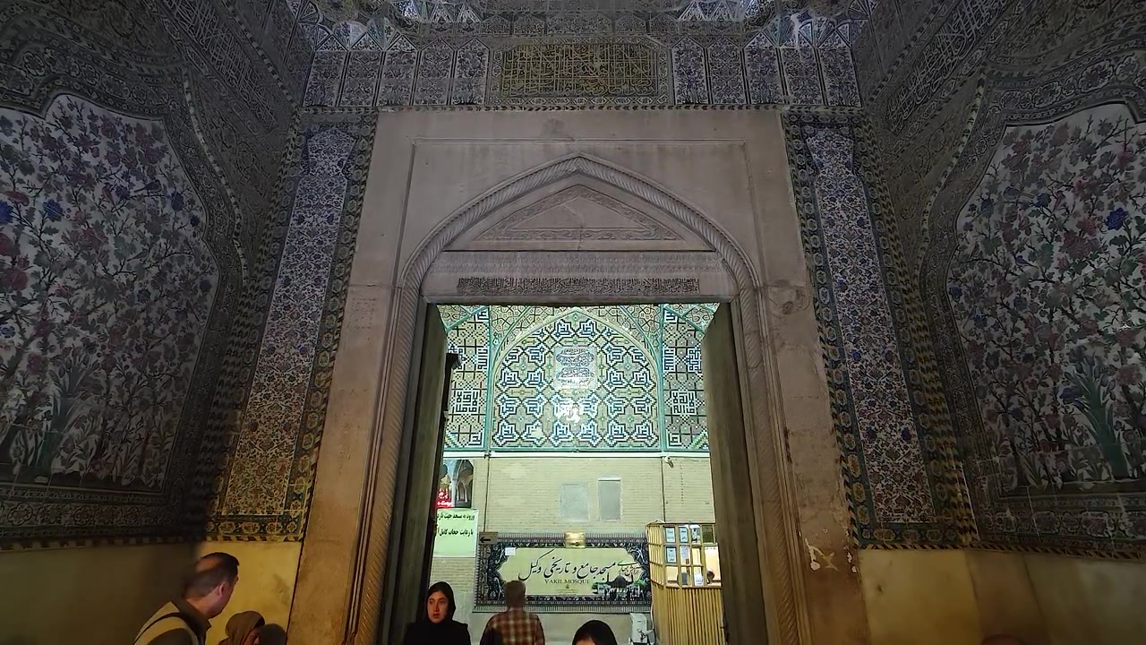 Persone che camminano attraverso l'ingresso ornato di una storica moschea persiana
