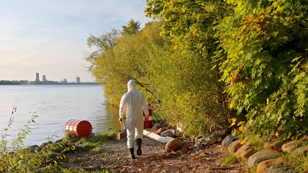 Person in protective suit by river, testing water pollution, environmental care