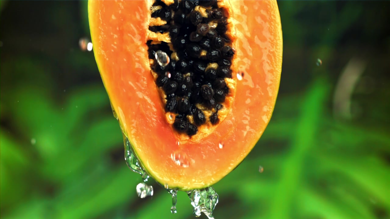 Acqua che gocciola su mezza papaya fresca al rallentatore