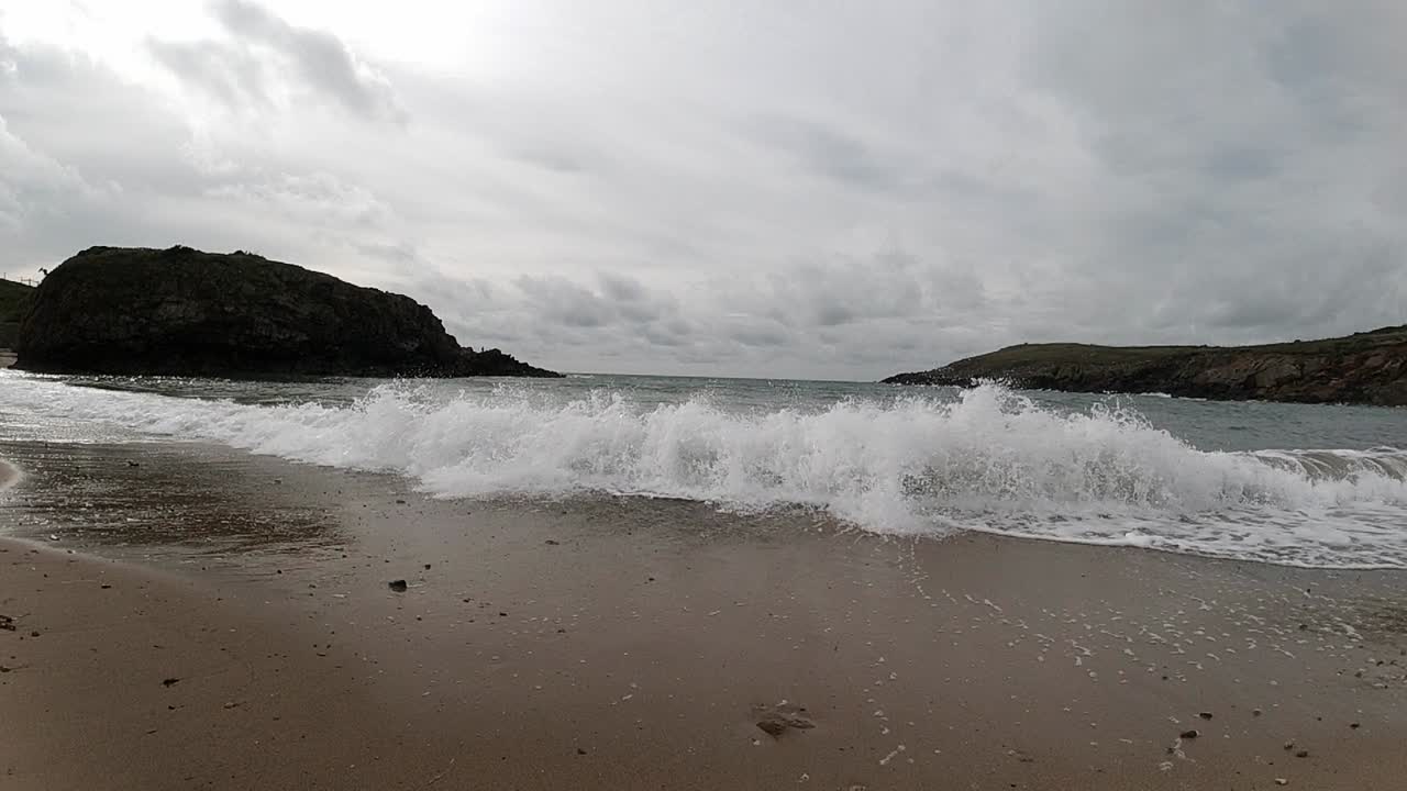 수평선을 가로지르는 섬 산들과 모래사장에 충돌하는 슬로우 모션 조수