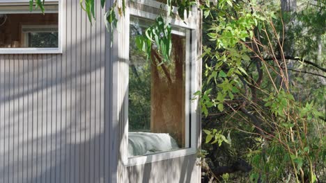 Cinematic-view-of-tiny-cabin-bedroom-window-looking-out-into-the-forest