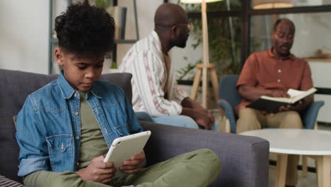 black kid playing with tablet at home