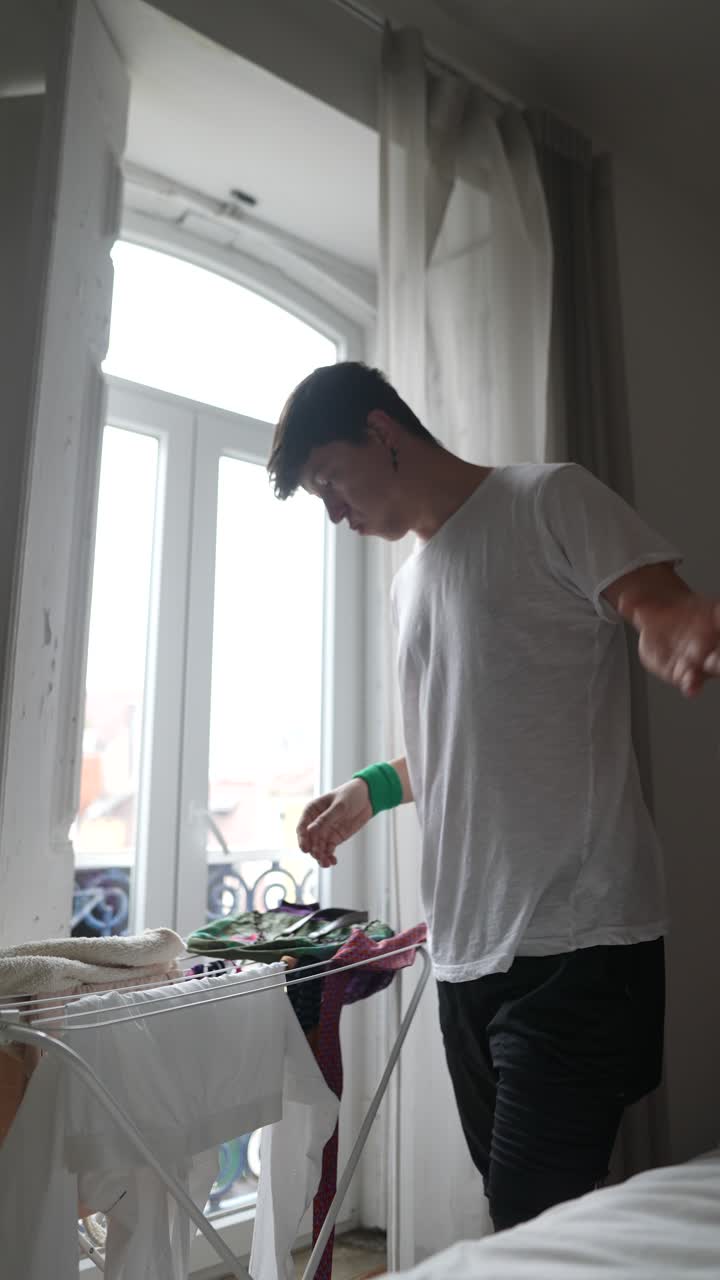Young Man Drying Clothes in Room