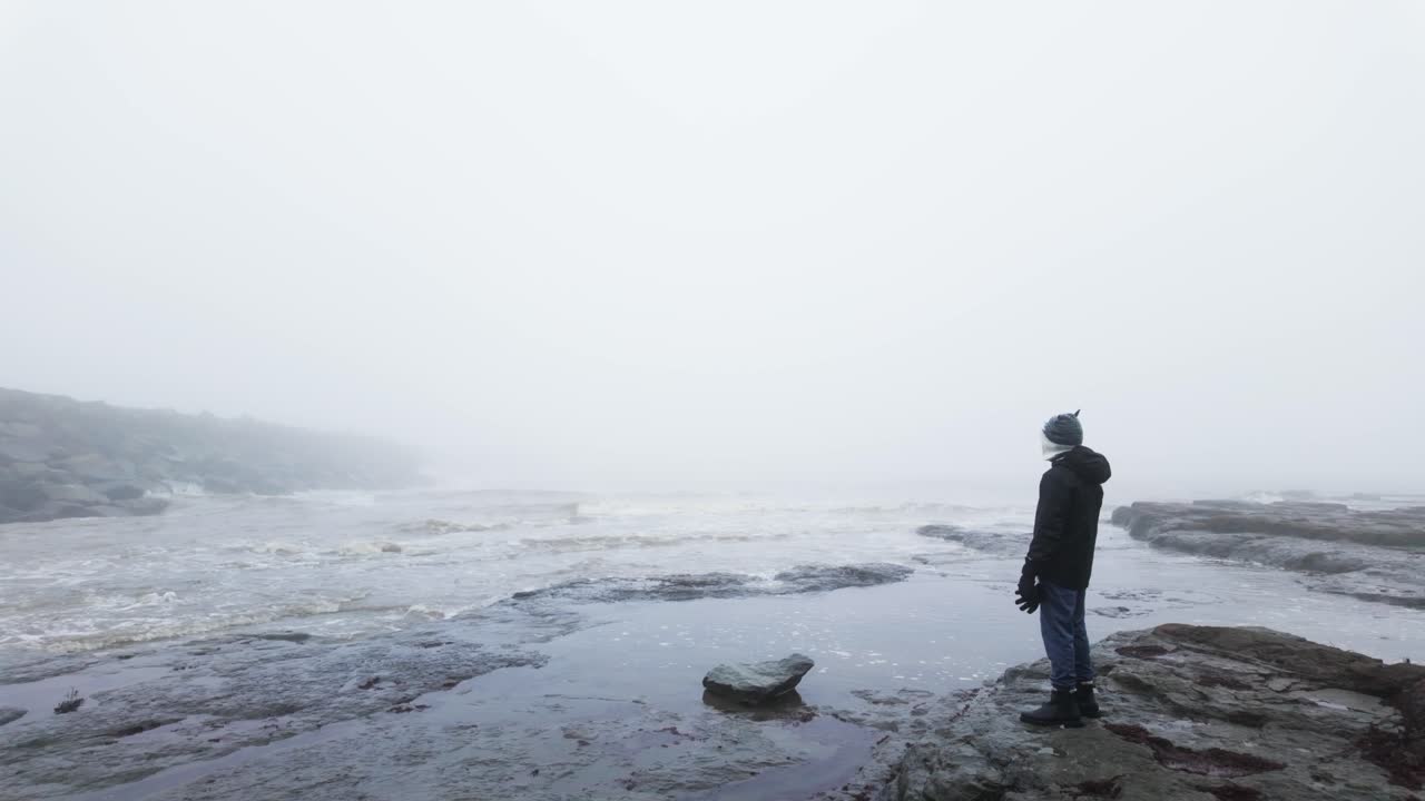 niño de pie en las rocas en un paisaje costero