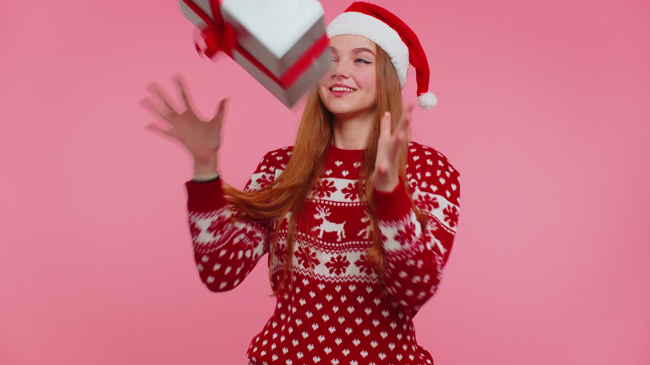 chica alegre en la navidad santa suéter recibiendo caja de regalos, expresando asombro felicidad
