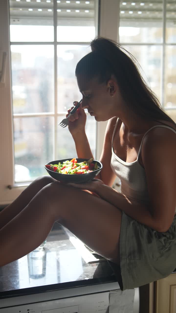 mujer comiendo ensalada saludable junto a la ventana
