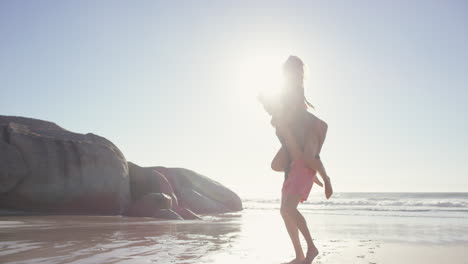 attractive man giving girlfriend piggyback couple enjoying nature  on the beach
