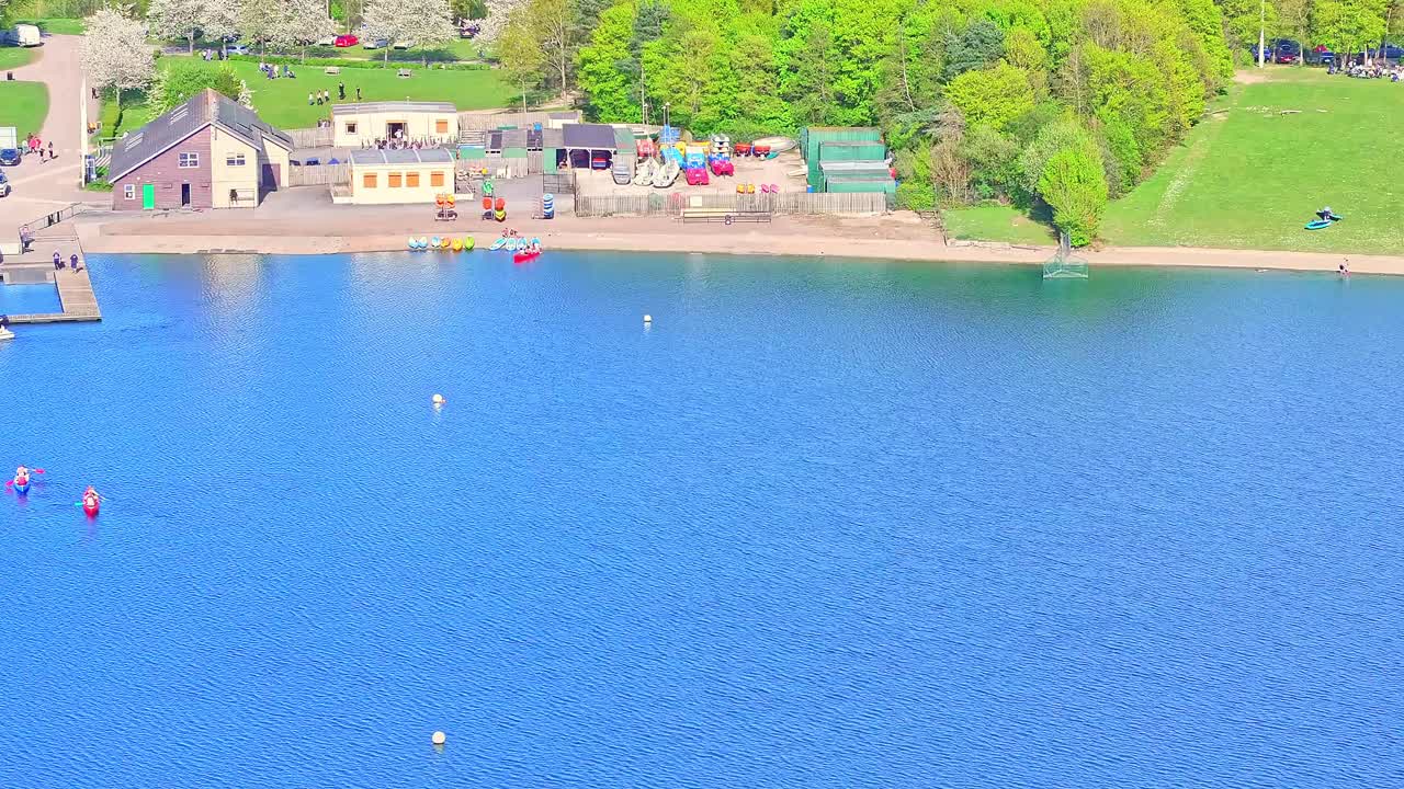 Aerial: canoes on the lake during the day in Rother Valley Country Park in the Metropolitan Borough of Rotherham, South Yorkshire, England, establishing drone shot