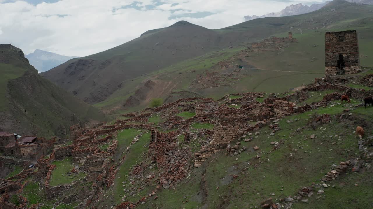 zona montañosa con antiguas ruinas, vacas que pastan y una pequeña aldea