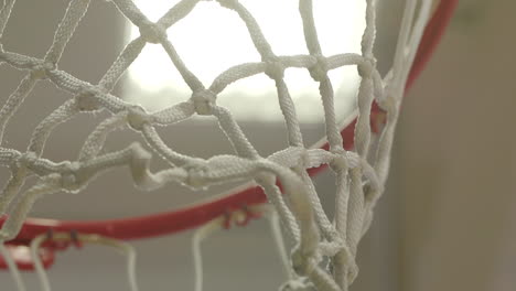 close up, rack focus of new basketball net and rim in an empty gym