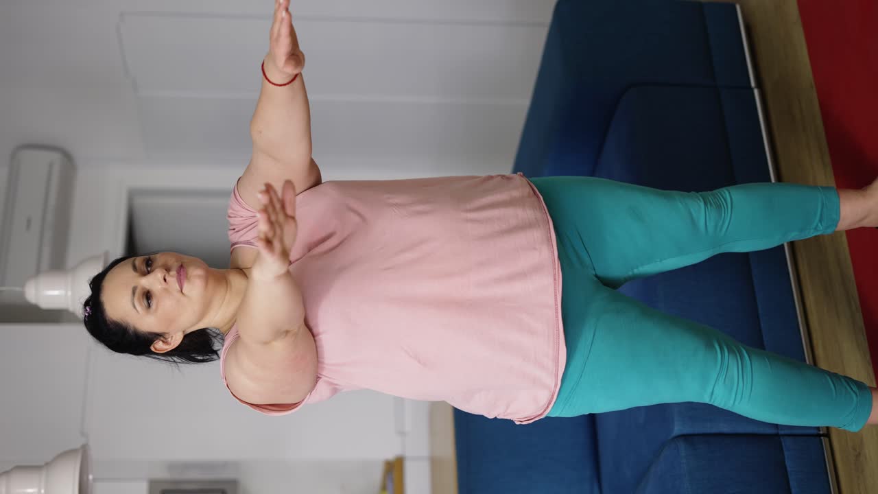 Brunette young woman in sportswear exercising to lose weight, practicing squats at home