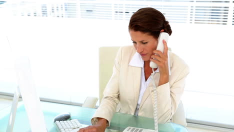 mujer de negocios trabajando en su escritorio y contestando el teléfono