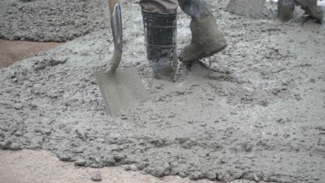 primer plano de un trabajador trabajando con su pala en hormigón húmedo