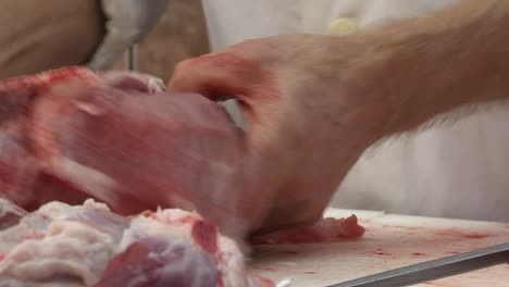 butcher cuts big piece of raw meat with sharp knife, closeup