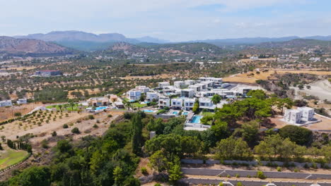 panoramic drone shot circling a hill with luxury vacation villas, in sunny greece
