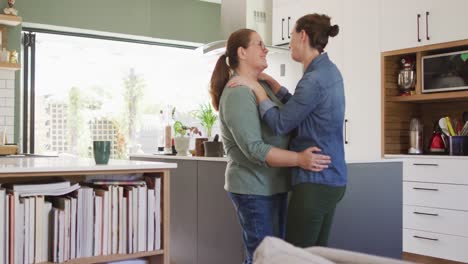 Caucasian-lesbian-couple-smiling-and-dancing-in-kitchen