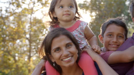 padres de raza mixta cargando a sus hijos en un parque