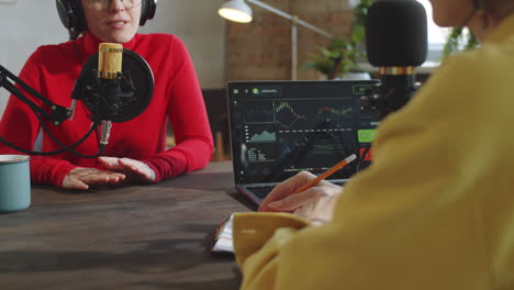 two women speaking in microphones while recording podcast