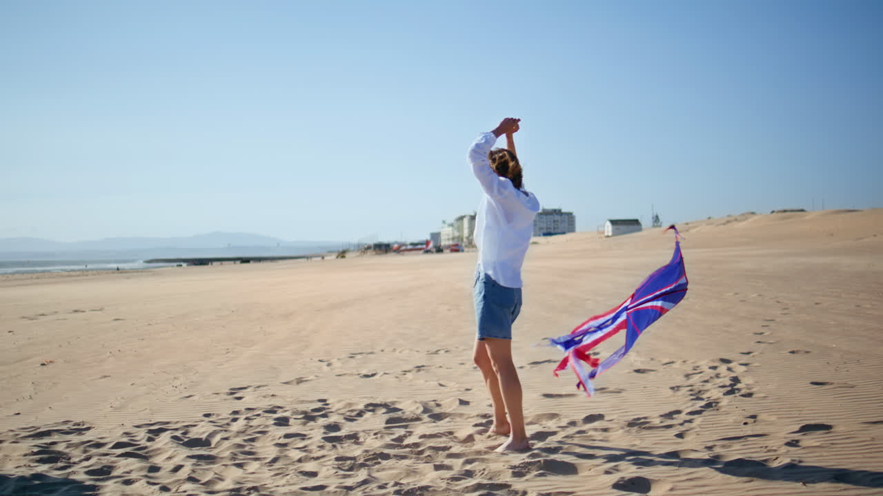 Happy family launching kite at summer sandy beach. Playful boy hugging mother