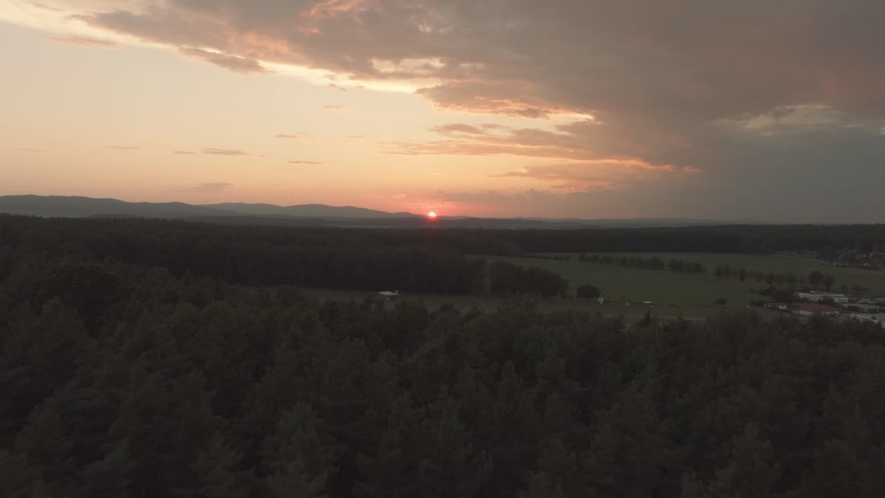 disparo dramático y épico de drones de los bosques y campos con montañas en el fondo vista de pájaro, durante una puesta de sol o un amanecer crepúsculo o amanecer