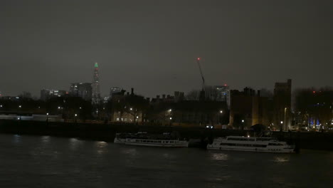 london skyline at night along the bank of the river thames with the shard in the background