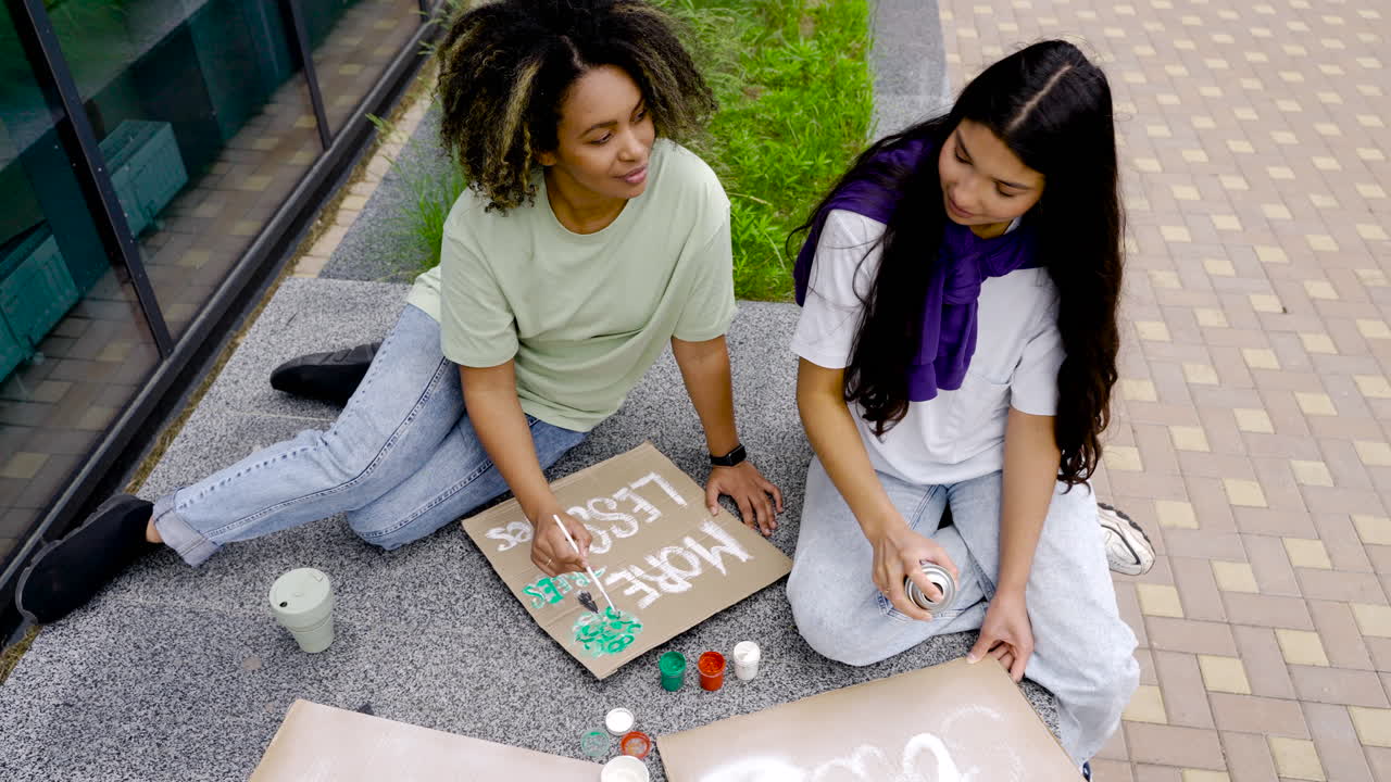 mujeres jóvenes terminando sus pancartas con pintura para demostración