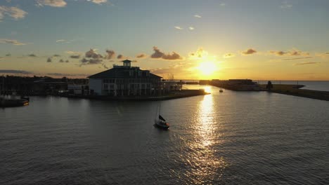 Sunsetting and sailboat heading into the marina drone view