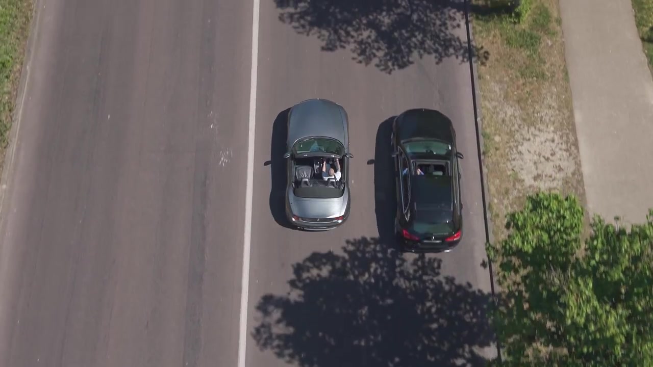 Il drone segue un'auto cabriolet con capote abbassata sulla strada del Bois de Boulogne a Parigi.