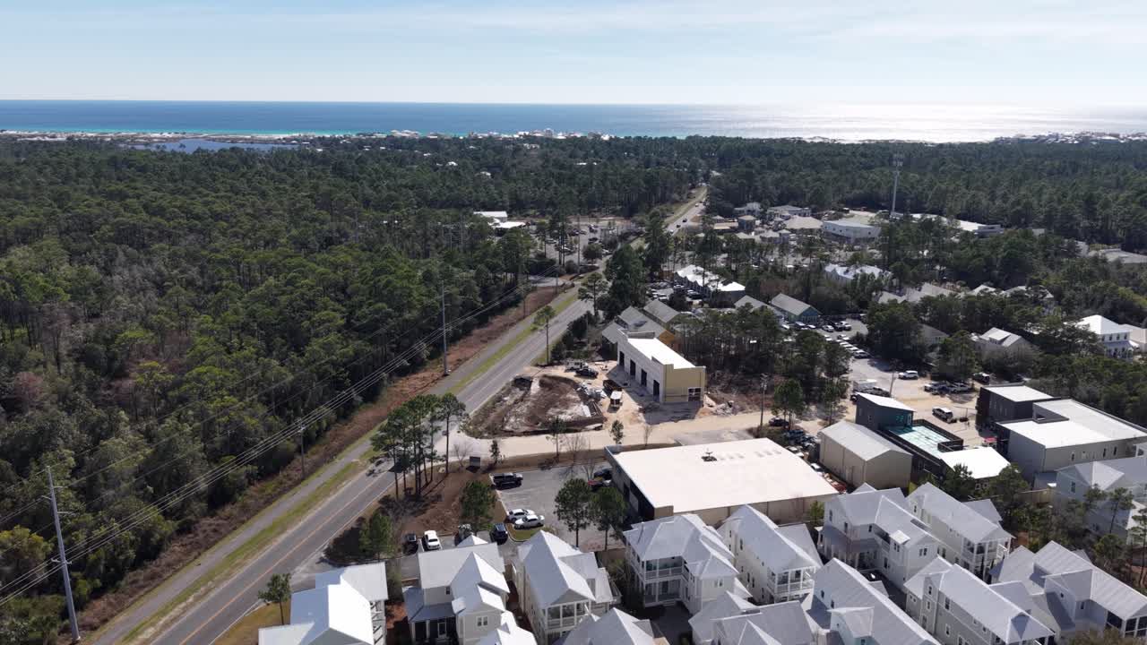 Volo drone ascendente sopra un'area residenziale costiera con case bianche di nuova costruzione, 30A, Florida, USA.