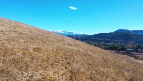 aerial over farm fields reveals the ojai valley and snow covered topatopa mountains in winter