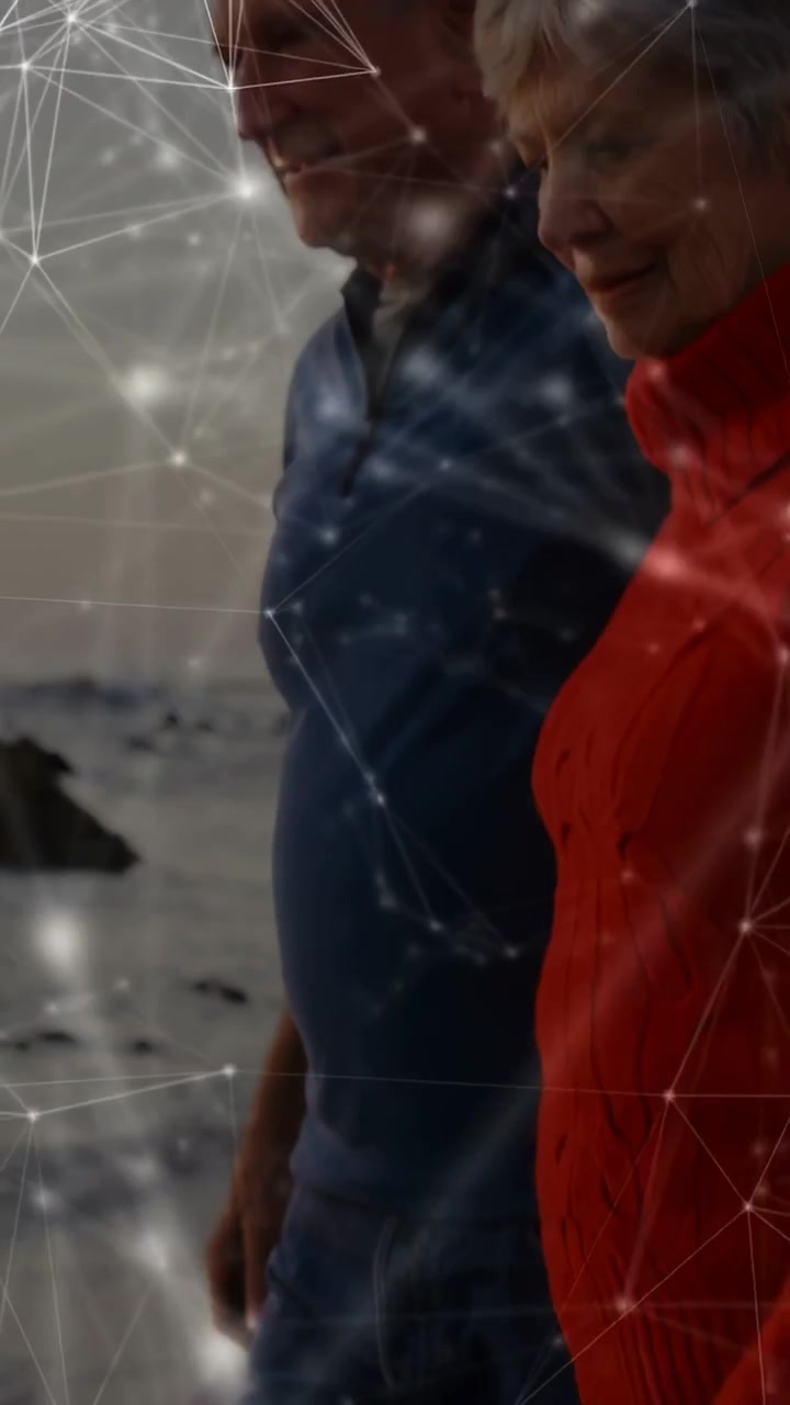 Vertical video: Two seniors walking shore as camera rises, activating node overlay showing vitals