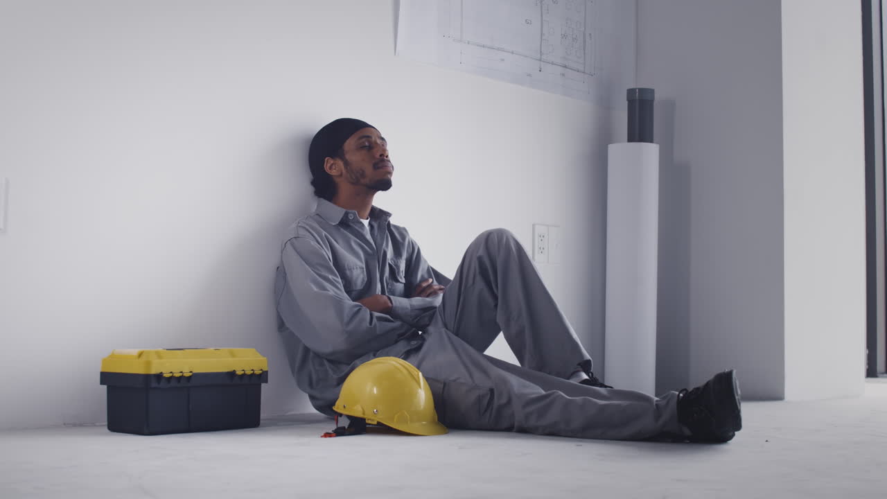 Tired Black Man Sleeping during Break at Work on Construction Site