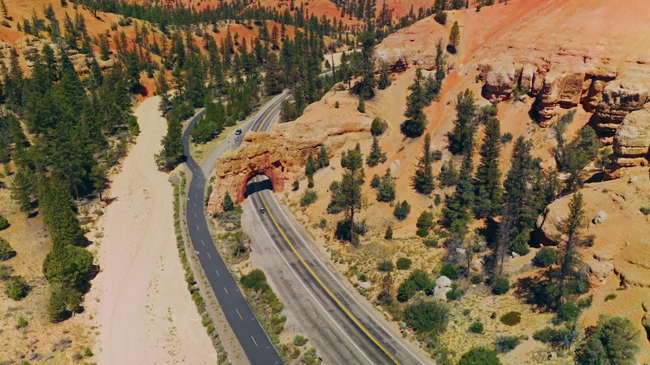 Rocky arch over the motorway in National park in United States. Bright sunny day in Arches Canyons, Utah. Aerial view.