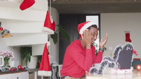 Happy-african-american-man-wearing-santa-hat,-using-laptop-for-video-call