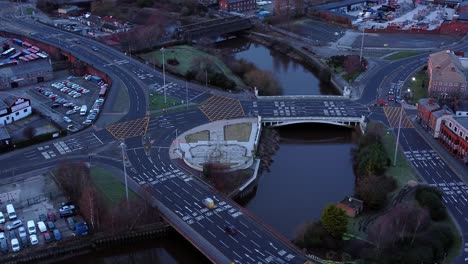 Aerial-early-morning-city-street-traffic-commuting-intersection-lanes-crossing-curved-river-orbit-right-looking-down