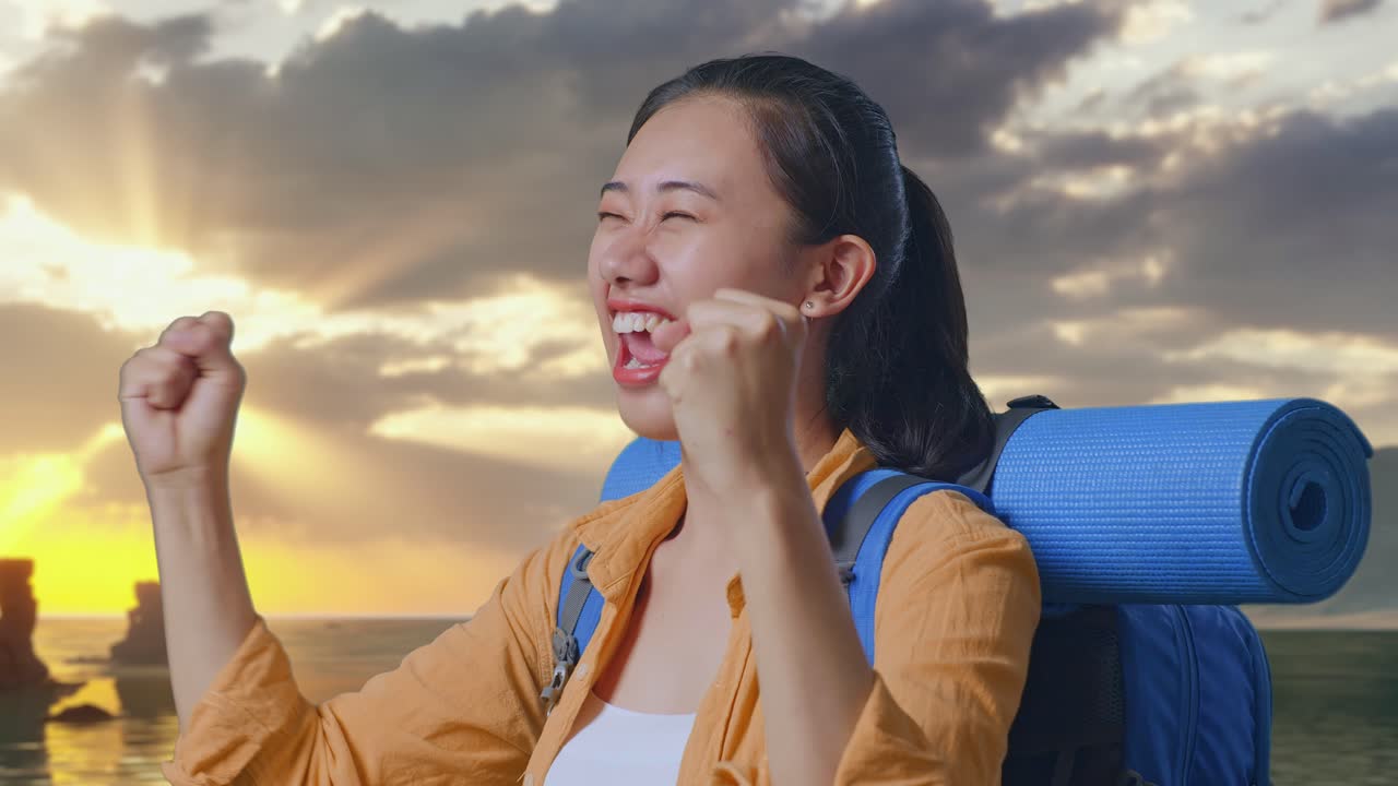 夕焼け時にビーチに立ち、成功を祝って叫び、目標を達成したことを喜ぶ登山用バックパックを背負ったアジア人女性ハイカーのクローズアップサイドビュー