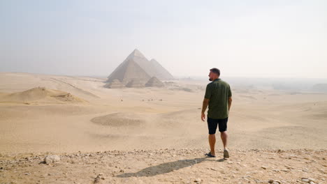 a tourist approaching the pyramids while taking in the view of the giza plateau near cairo, egypt - tracking shot