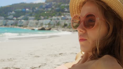 Side-view-of-Caucasian-woman-in-hat-relaxing-on-the-beach-4k