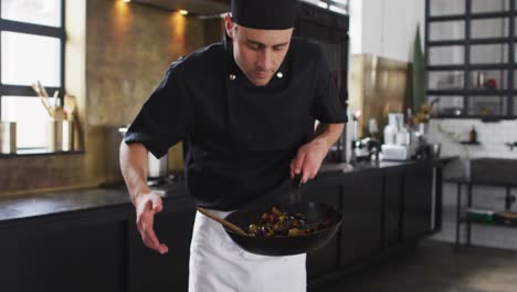 Caucasian-male-chef-preparing-a-dish-and-smiling-in-a-kitchen-