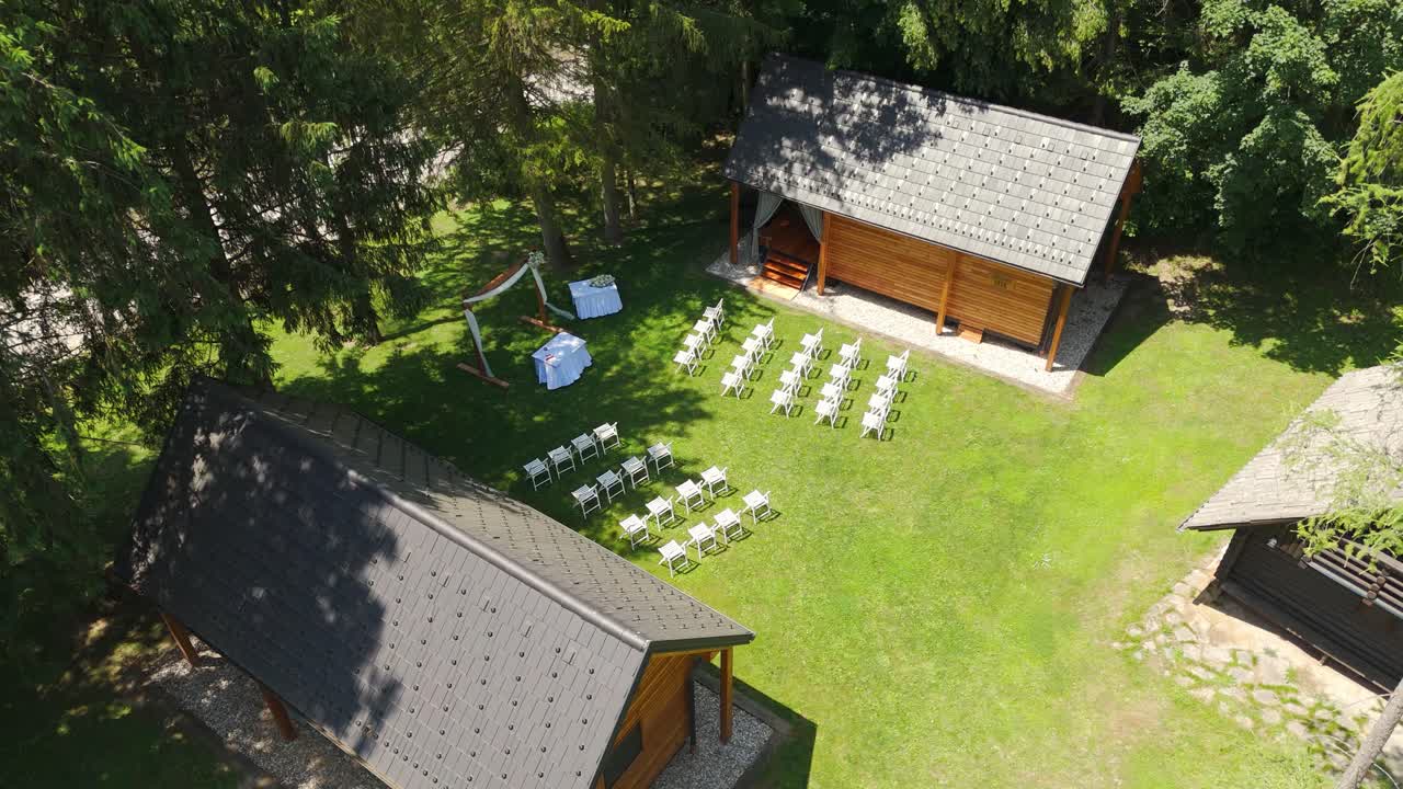 The setup with white chairs and a stage is ready for a wedding ceremony outdoors.