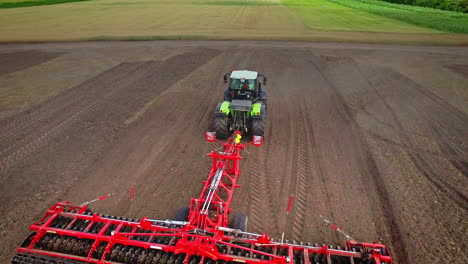 Agricultural-tractor-with-trailer-plowing-on-farming-field.-Agricultural-sector