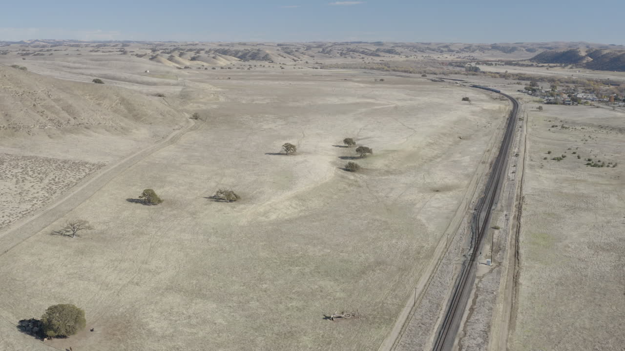 4K aerial static shot of Amtrak's Coast Starlight moving off toward the horizon.