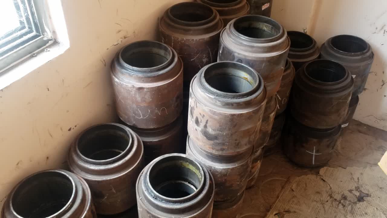 A storage area is depicted filleds with several large cylindrical objects that seem to be railway train wheelset bearings