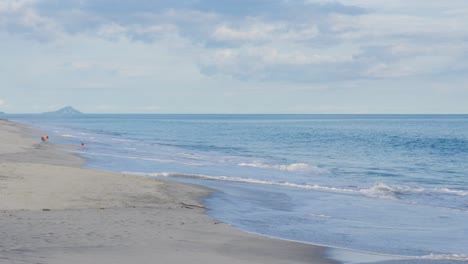 children in the distance playing in the crashing waves